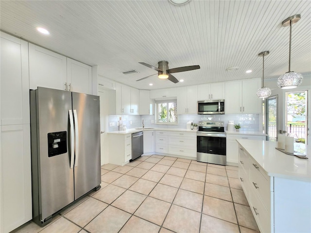 kitchen with light tile patterned floors, tasteful backsplash, appliances with stainless steel finishes, light countertops, and a sink