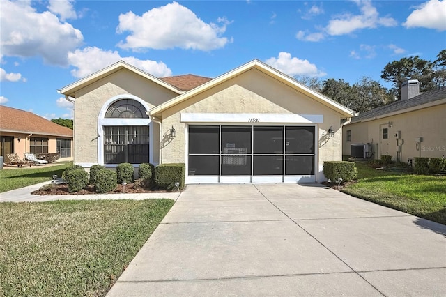 ranch-style home with a front yard, cooling unit, an attached garage, and stucco siding