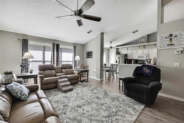 living room featuring lofted ceiling, ceiling fan, wood finished floors, and visible vents