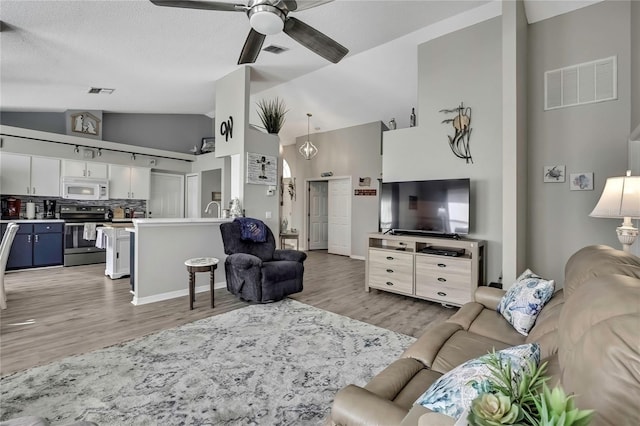 living room featuring light wood-type flooring, high vaulted ceiling, visible vents, and a ceiling fan