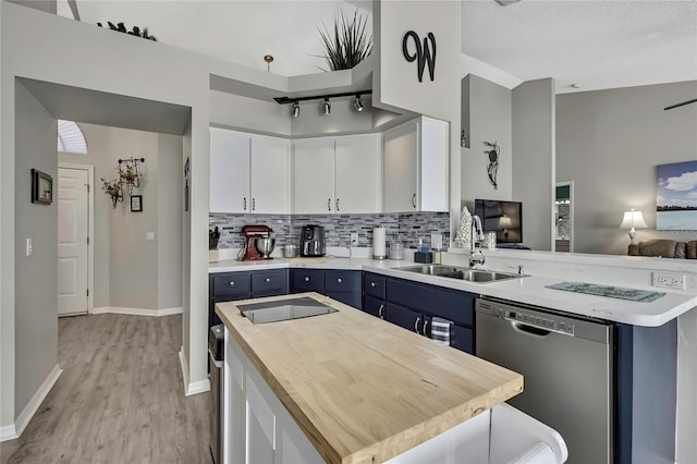 kitchen with blue cabinets, butcher block countertops, a sink, dishwasher, and tasteful backsplash