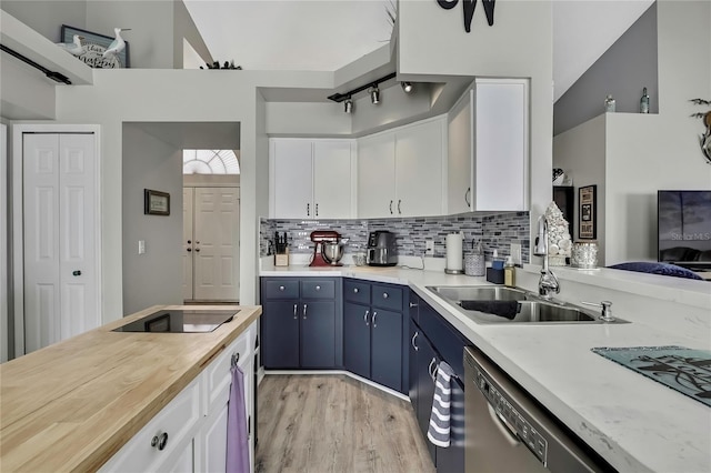 kitchen featuring black electric cooktop, a sink, white cabinets, blue cabinetry, and backsplash