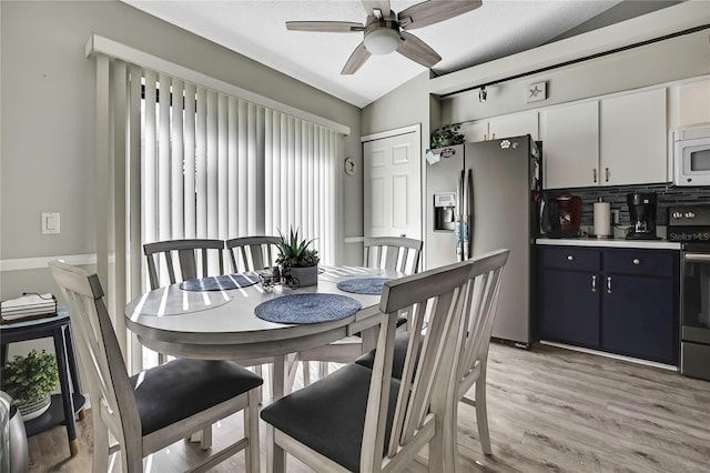 dining area featuring a ceiling fan, light wood-type flooring, and lofted ceiling