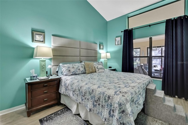 bedroom with lofted ceiling, baseboards, and wood finished floors