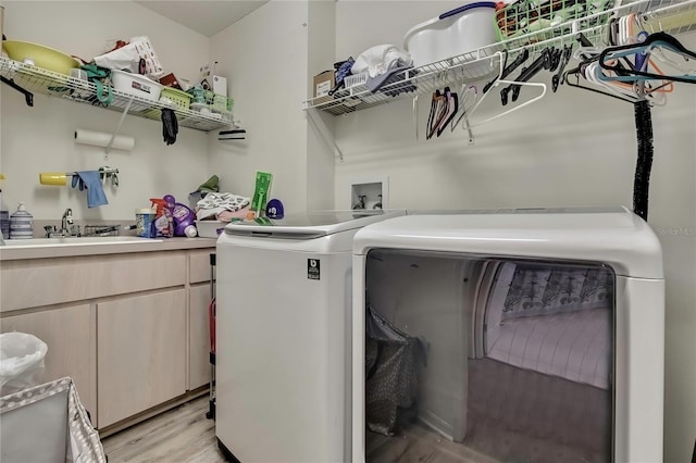 laundry room featuring laundry area, independent washer and dryer, a sink, and light wood-style flooring