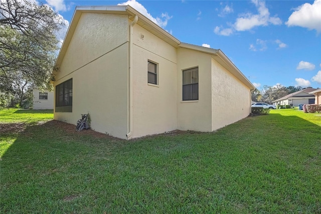 view of side of property featuring a lawn and stucco siding