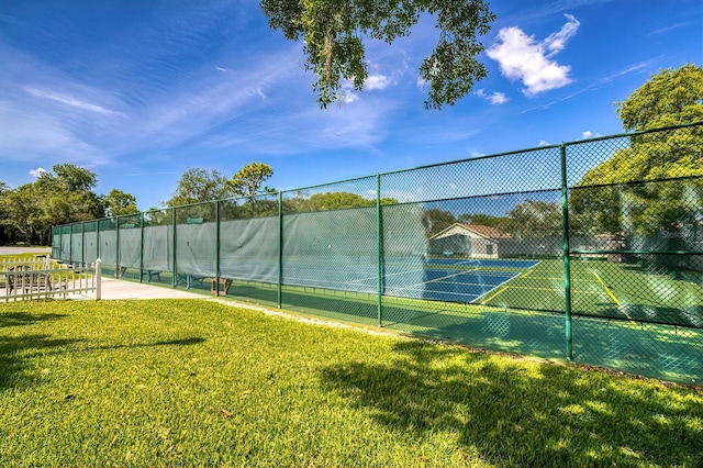 view of tennis court with fence and a lawn