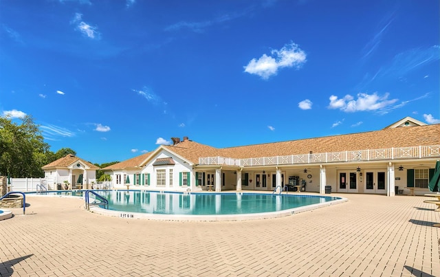 pool with a patio area, fence, and french doors