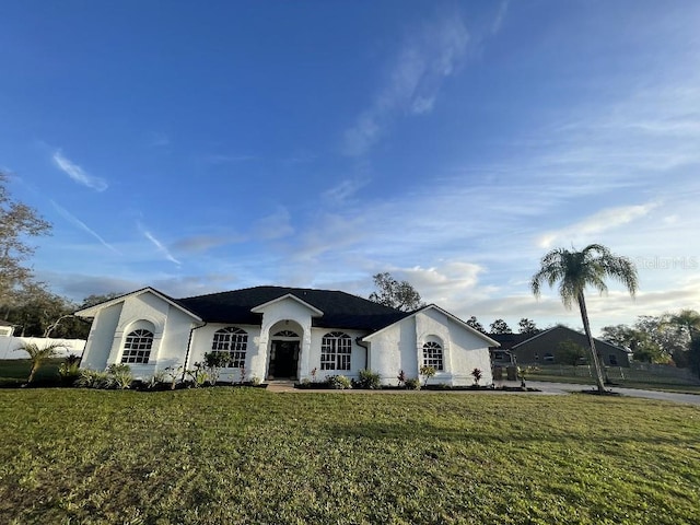 ranch-style home with a front lawn and stucco siding