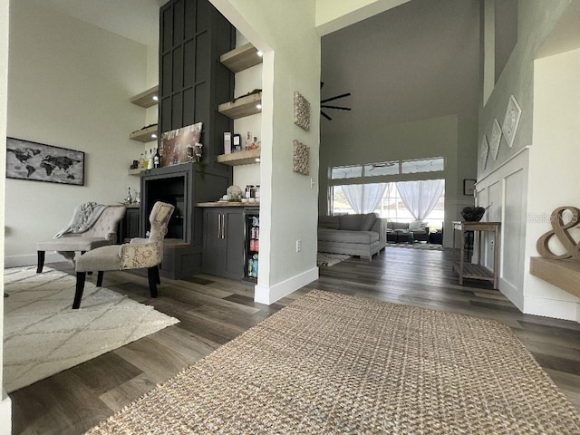 living area featuring wood finished floors, a towering ceiling, and baseboards