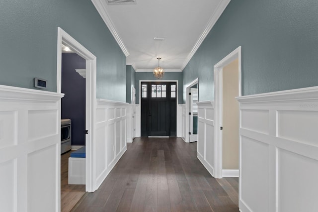 doorway with visible vents, wainscoting, ornamental molding, dark wood-type flooring, and a chandelier