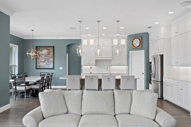 living room featuring visible vents, arched walkways, dark wood finished floors, and crown molding