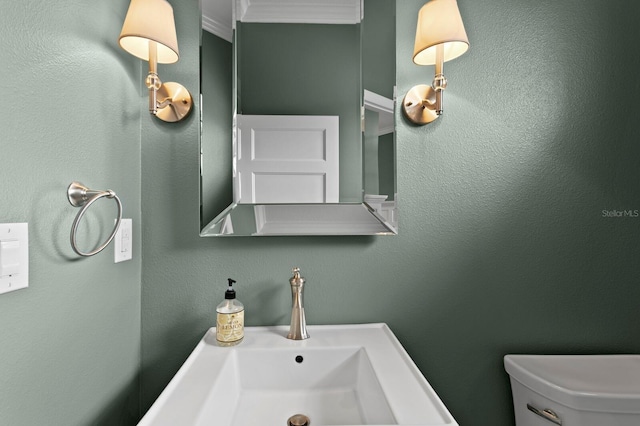 bathroom featuring a textured wall, a sink, and toilet