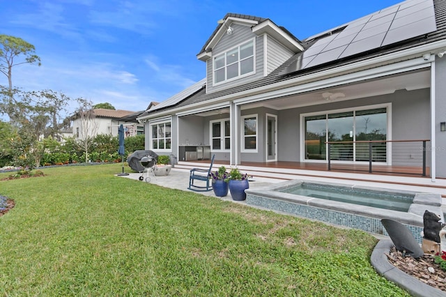 back of house with a yard, a patio area, solar panels, and an in ground hot tub