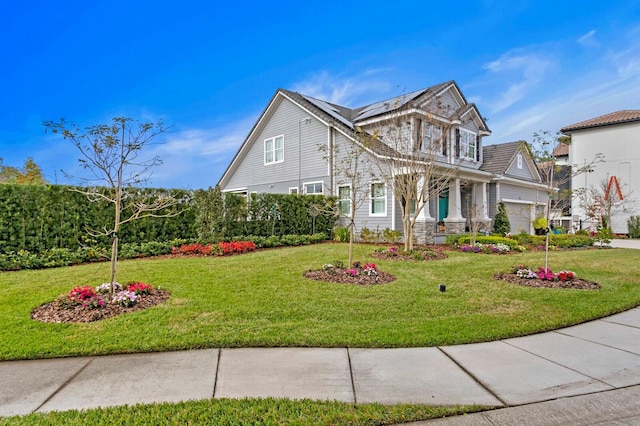 view of front of home with an attached garage, solar panels, and a front yard