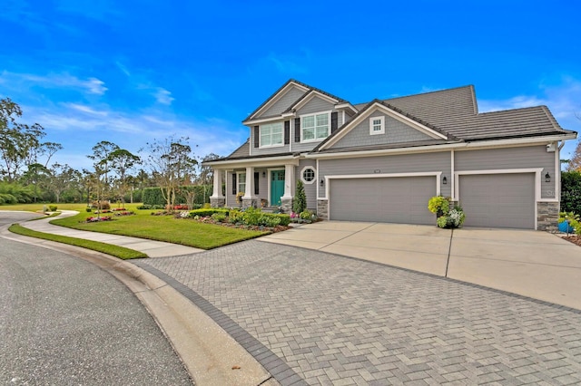 craftsman inspired home featuring concrete driveway, stone siding, a front lawn, and an attached garage