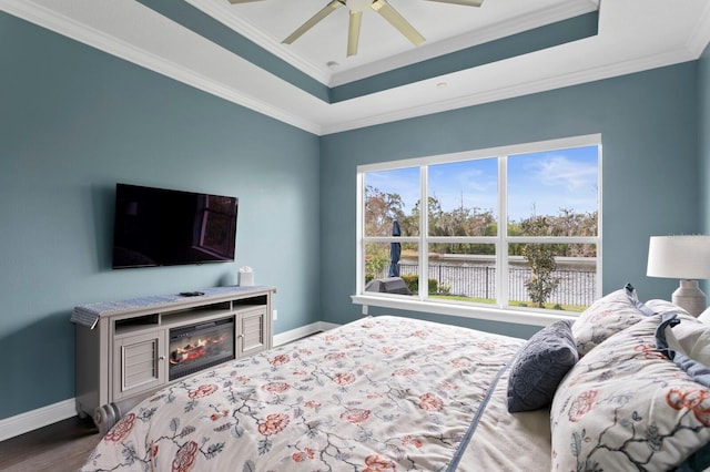 bedroom with baseboards, a raised ceiling, and crown molding