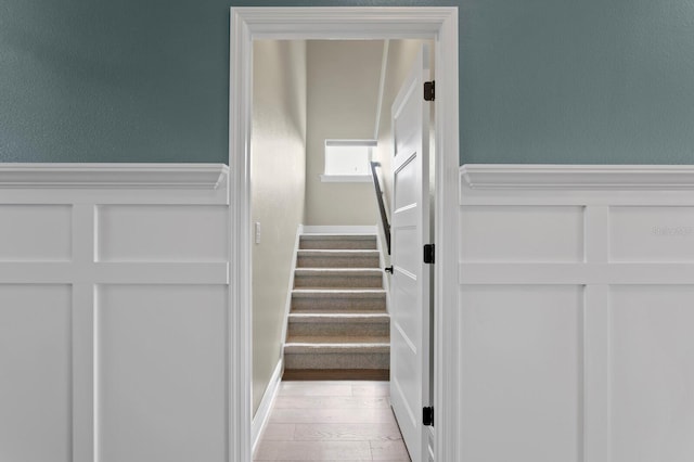 stairway featuring wainscoting and wood finished floors