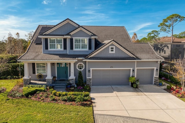 craftsman-style house featuring a garage, driveway, stone siding, a porch, and a front lawn