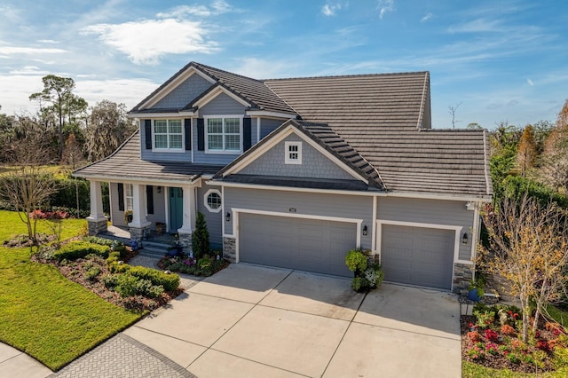 craftsman house with an attached garage, stone siding, a front lawn, and concrete driveway