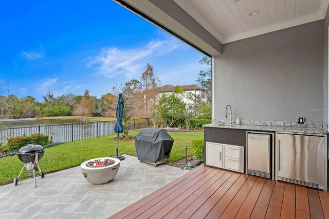 wooden deck featuring a yard, a fenced backyard, and a grill