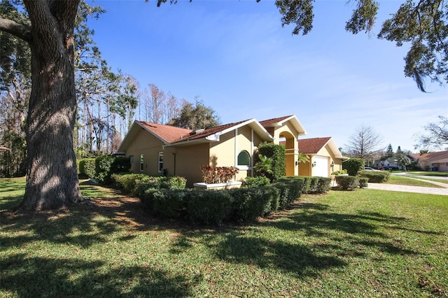 view of side of home with a garage, a lawn, and stucco siding