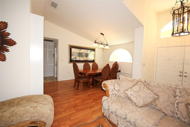 living room featuring vaulted ceiling, light wood-style flooring, and visible vents