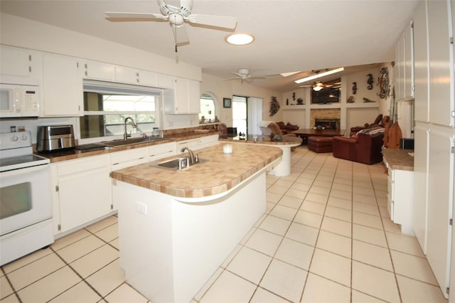 kitchen featuring light tile patterned floors, white appliances, a fireplace, and a sink