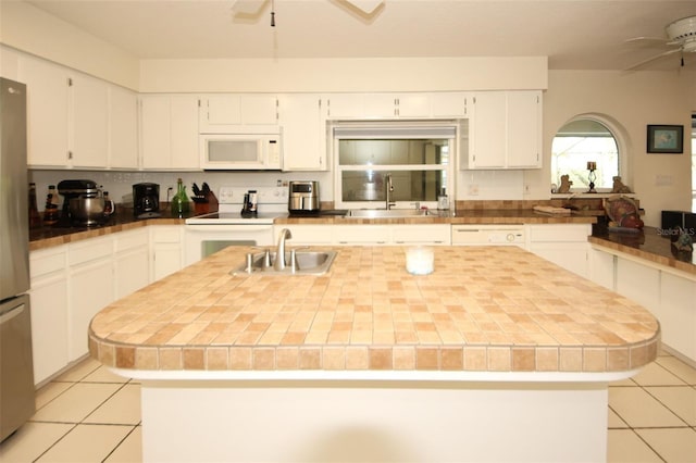 kitchen featuring white appliances, ceiling fan, and a sink