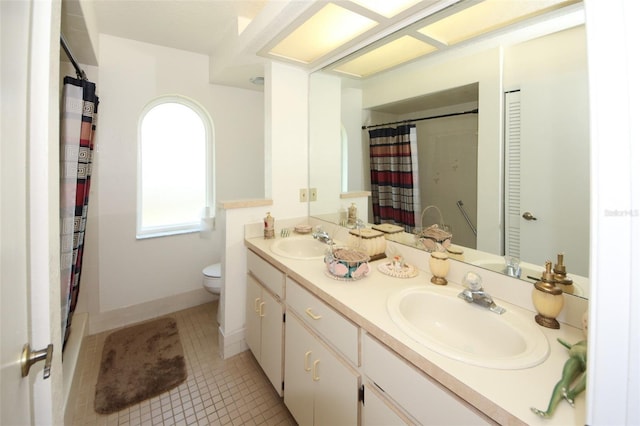 bathroom featuring double vanity, a sink, toilet, and tile patterned floors