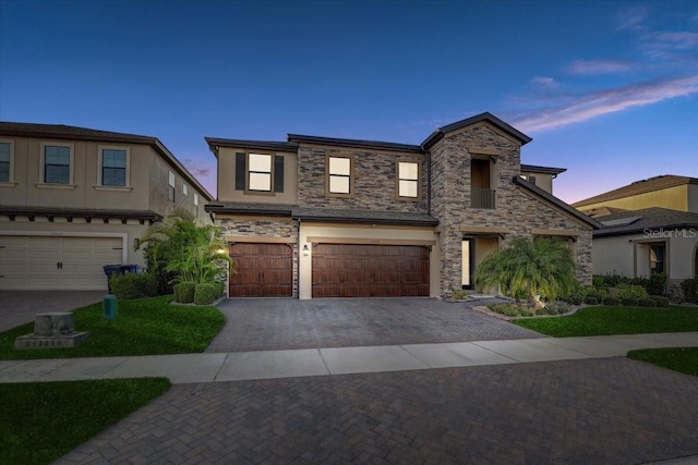 view of front of home featuring stone siding, decorative driveway, an attached garage, and stucco siding