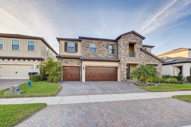 view of front of house featuring stone siding, stucco siding, an attached garage, decorative driveway, and a front yard