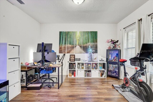 home office with visible vents, a textured ceiling, and wood finished floors