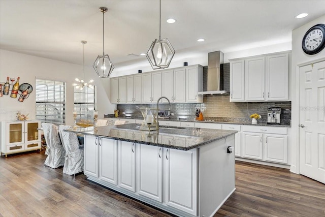 kitchen with a sink, a large island, wall chimney exhaust hood, tasteful backsplash, and dark wood finished floors