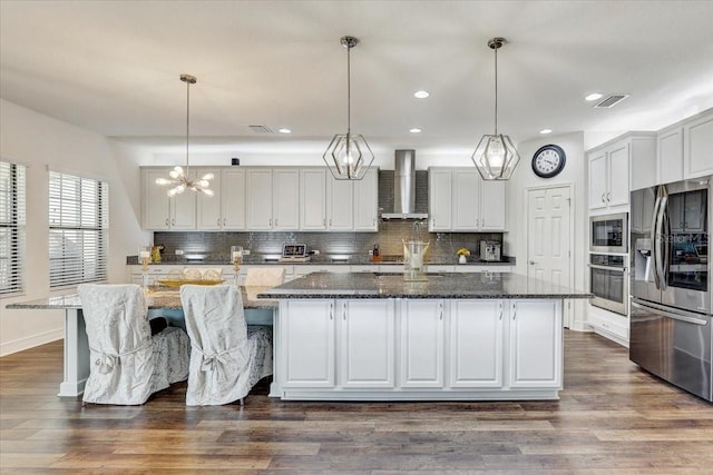 kitchen with dark wood-style flooring, a large island, decorative backsplash, appliances with stainless steel finishes, and wall chimney range hood