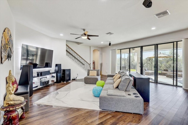 living room with arched walkways, stairs, dark wood-style floors, and visible vents