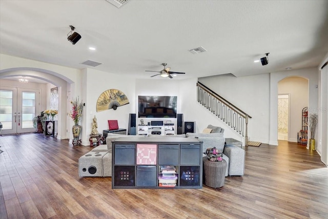 living area featuring visible vents, arched walkways, stairway, wood finished floors, and french doors