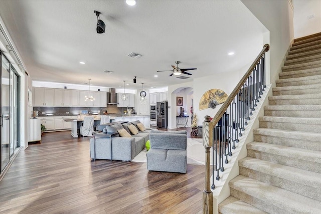 living area featuring arched walkways, visible vents, ceiling fan, dark wood-type flooring, and stairs