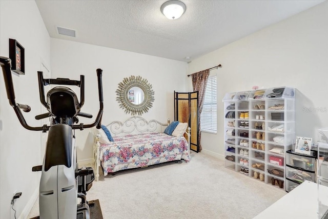 carpeted bedroom featuring visible vents, a textured ceiling, and baseboards