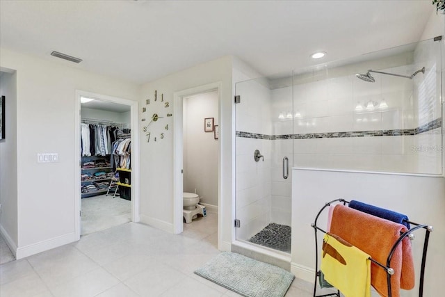 full bath with visible vents, baseboards, toilet, a walk in closet, and a shower stall