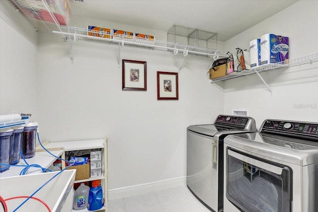 laundry room featuring tile patterned floors, laundry area, baseboards, and separate washer and dryer