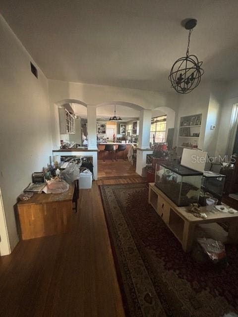 hall with arched walkways, visible vents, and wood finished floors