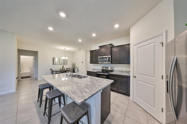 kitchen featuring an island with sink, a breakfast bar, stainless steel appliances, a sink, and light tile patterned flooring