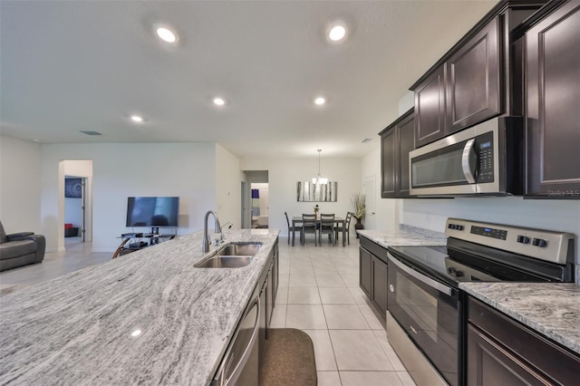 kitchen with open floor plan, stainless steel appliances, light stone counters, and a sink