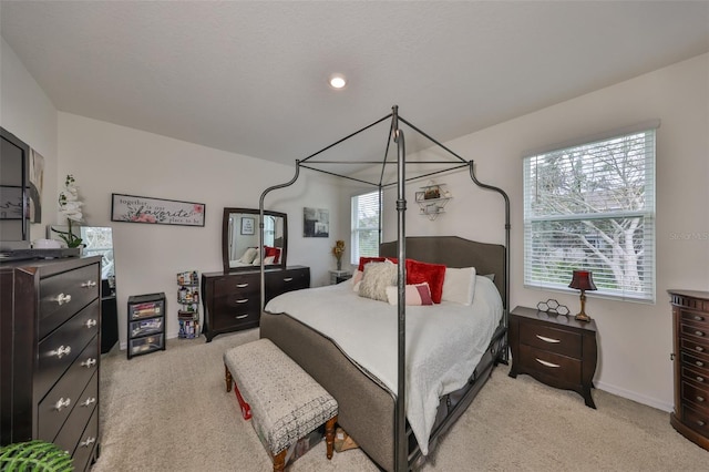 bedroom with baseboards, multiple windows, and light colored carpet