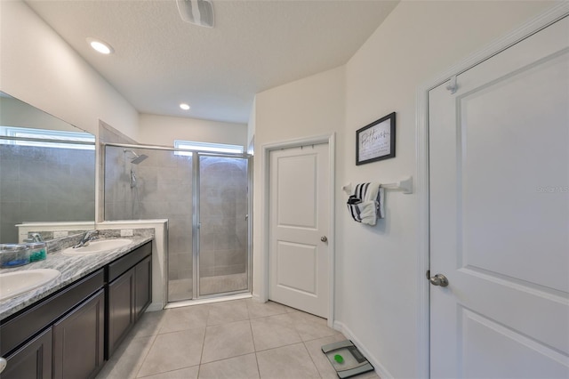 full bath with double vanity, tile patterned flooring, a shower stall, and a sink