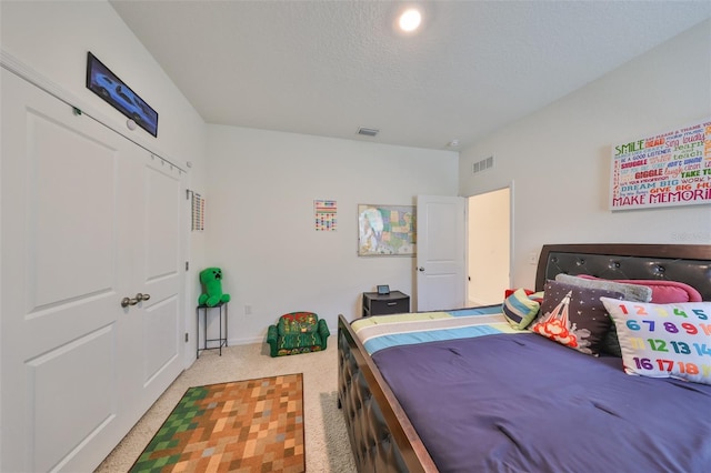 bedroom featuring light carpet, a textured ceiling, and visible vents