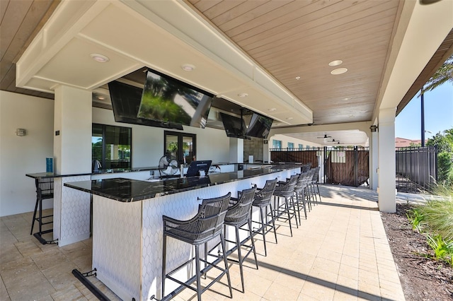 kitchen featuring wooden ceiling, recessed lighting, a kitchen breakfast bar, open floor plan, and dark stone countertops