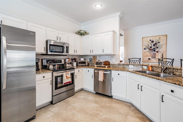 kitchen with a sink, appliances with stainless steel finishes, ornamental molding, and white cabinets