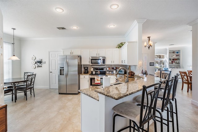 kitchen with light stone counters, visible vents, a peninsula, a sink, and appliances with stainless steel finishes